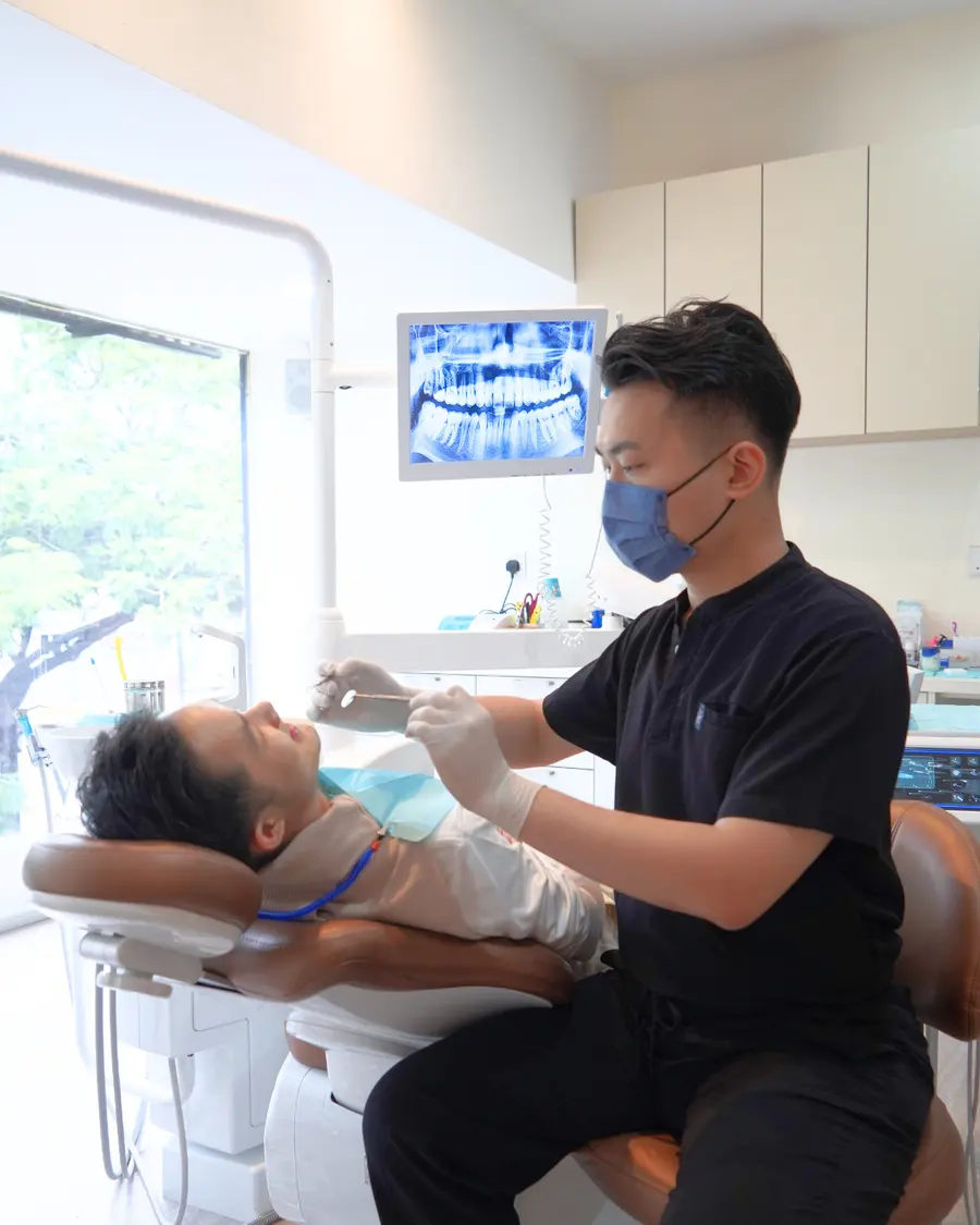 Dentist seated at the chair during treatment with an X-ray on the monitor