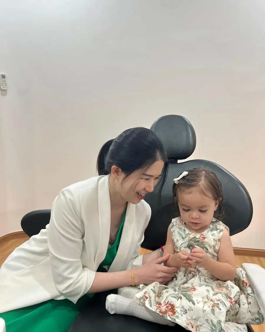 Dentist kneeling beside a toddler in the dental chair