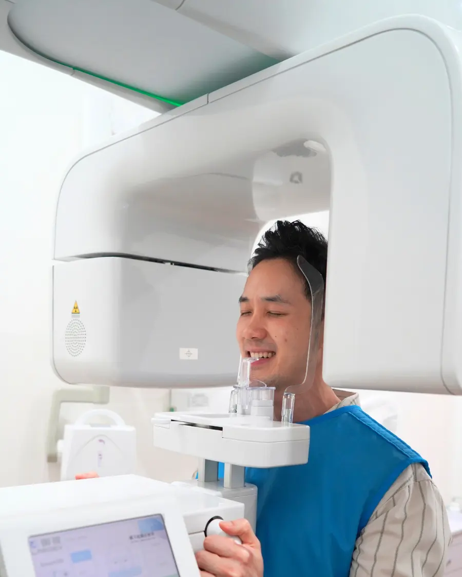 Man standing in the panoramic X-ray machine wearing a lead apron