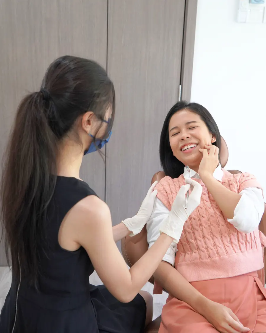 Woman holding her cheek in pain while the dentist listens